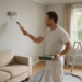 Interior of a freshly painted living room showing a professional painter using a roller brush, showcasing modern paint color trends.