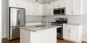 Bright, modern kitchen featuring white shaker cabinets, marble countertops, and stainless steel appliances in a remodeled space.