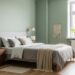 A serene bedroom with sage green walls, soft bedding, wooden nightstand, and natural light illuminating a potted plant in the corner.