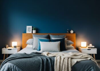 Modern bedroom featuring a navy blue accent wall, minimalist decor, wooden headboard, and soft neutral bedding for home decor inspiration.