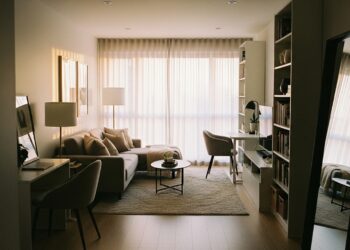 A long, narrow living room with modern furniture, vertical shelving, soft lighting, and smart zoning for functional, cozy space