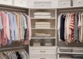 A pristine, well-organized walk-in closet with color-coded clothes, neatly folded sweaters, and storage boxes. The image showcases efficient space utilization and a clean, stress-free environment, illustrating how to organize a closet effectively.